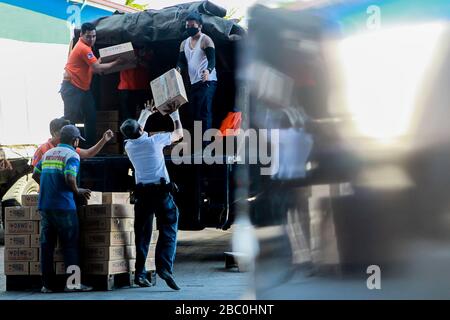 (Pasay City, Pasay City. April 2020. Freiwillige, die Gesichtsmasken tragen, laden am 2. April 2020 Kisten mit Hilfsgütern auf einen Lastwagen in einem Regierungslager in Pasay City, den Philippinen. Die Philippinen hatten am Donnerstag alle, die in Gebieten unter verstärkter Gemeinschaftsquarantäne lebten, verpflichtet, Gesichtsmasken oder andere Schutzausrüstungen zu tragen, wenn sie ihre Häuser verlassen, um die Verbreitung von COVID-19 zu verlangsamen. Kredit: Xinhua/Alamy Live News Stockfoto