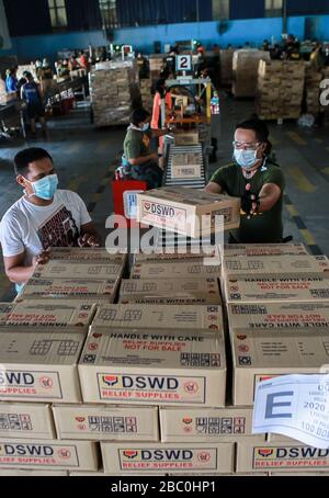 (Pasay City, Pasay City. April 2020. Mitglieder der philippinischen Küstenwache, Polizisten und Freiwillige, die Gesichtsmasken tragen, bereiten Hilfsgüter als Hilfe für Gemeinden vor, die unter verstärkter Gemeindequarantäne in einem Regierungslager in Pasay City auf den Philippinen am 2. April 2020 stehen. Die Philippinen hatten am Donnerstag alle, die in Gebieten unter verstärkter Gemeinschaftsquarantäne lebten, verpflichtet, Gesichtsmasken oder andere Schutzausrüstungen zu tragen, wenn sie ihre Häuser verlassen, um die Verbreitung von COVID-19 zu verlangsamen. Kredit: Xinhua/Alamy Live News Stockfoto