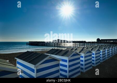 Reihe von Strandhütten am Strand neben dem Pier in Hastings, East Sussex, Großbritannien Stockfoto