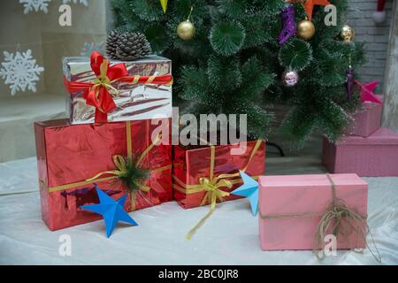 Geschenkschachteln am weihnachtsbaum. Frohes neues Jahr. Feiern Sie Weihnachten zu Hause. Winterurlaubseinkäufe. Einkaufsverkauf. Geschenklieferung. Rot, Rosa, Silber Stockfoto