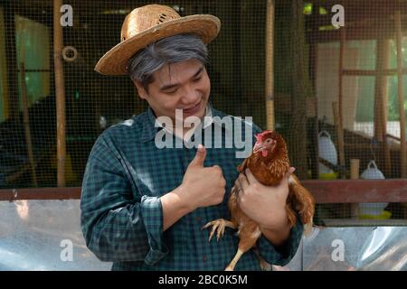 Asiatische Bauern halten Hühner. Auf einer Hühnerfarm in der eigenen Wohnung, mit einem glücklichen Geste
