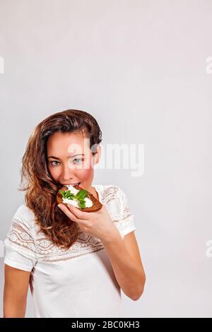 Frau, die Brot mit Frischkäse isst Stockfoto