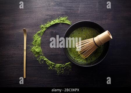 Matcha-Pulver. Organische grüne Matcha-Teezeremonie. Gesundes Getränk. Traditionelles japanisches Getränk auf schwarzem Holzhintergrund Stockfoto