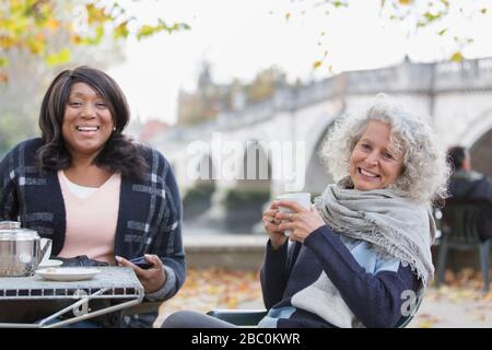 Portrait lächelnd, fröhliche aktive Seniorinnen Freunde trinken Kaffee im Herbstparkcafé Stockfoto