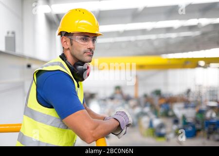 Seriöse männliche Aufseher lehnen sich werksseitig auf das Bahnsteiggeländer Stockfoto