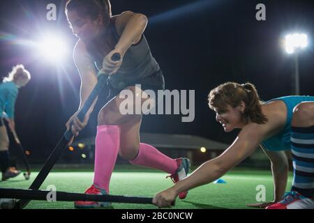 Ermittelte Feldhockeyspielerinnen, die mit Hockeyschlägern greifen Stockfoto