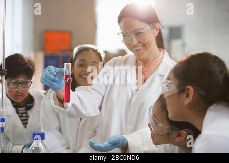 Lächelnde Chemielehrerin und Studenten, die wissenschaftliche Experimente im Laborunterricht durchführen Stockfoto