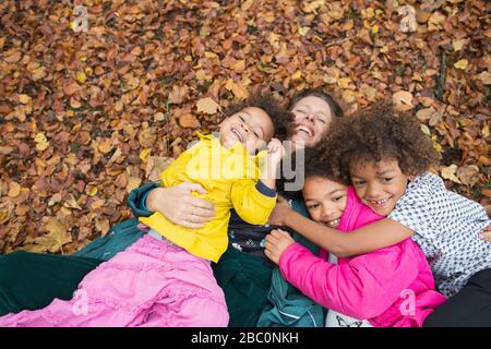 Porträt glückliche Mutter und Kinder legen in Herbstlaub Stockfoto