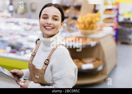 Portrait fröhlicher, selbstbewusster weiblicher Lebensmittelhändler mit digitalem Tablet im Supermarkt Stockfoto