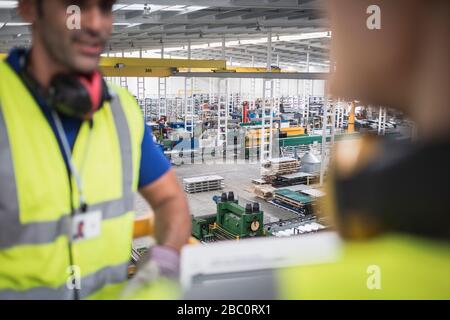 Männliche Arbeiter reden auf der Plattform in der Fabrik Stockfoto