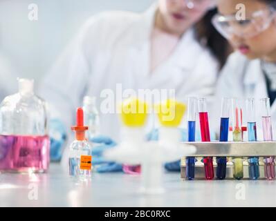 Studenten von Mädchen führen wissenschaftliche Experimente hinter Reagenzgläsern und Flaschen im Laborunterricht durch Stockfoto