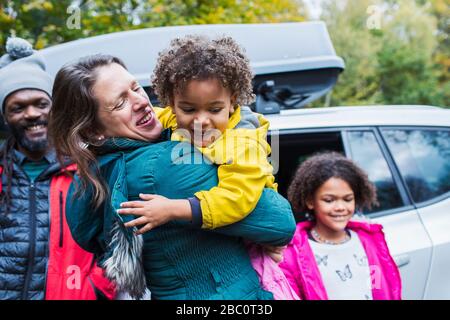 Glückliche Mutter und Tochter umarmen sich außerhalb des Autos Stockfoto