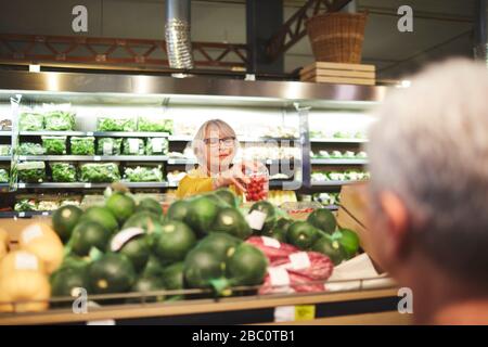 Seniorin kauft Tomaten im Bereich Supermarktprodukte ein Stockfoto