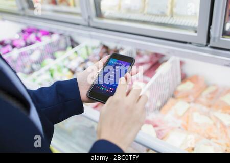Frau mit Einkaufslisten-App, Einkauf im Supermarkt Stockfoto