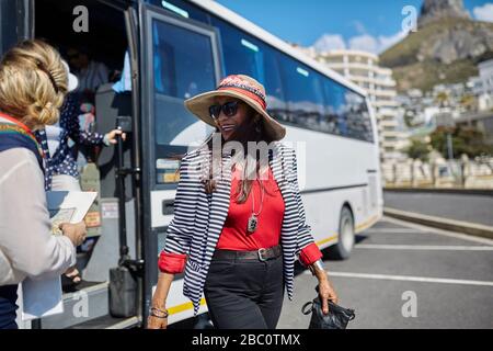Lächelnde aktive Seniorin Tourist, die vom Reisebus abkommt Stockfoto