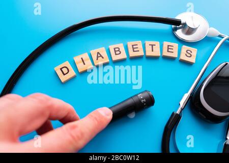 Holztext für Diabetes. Flache Laienzusammensetzung mit Blutzuckermessgerät und Stethoskop auf hellblauem Hintergrund. Leerzeichen für Text Stockfoto