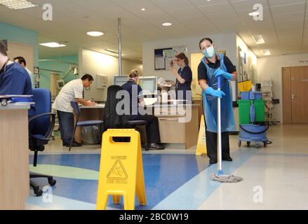 Ein Krankenhausreiniger trägt eine schützende Gesichtsmaske, während sie den Boden eines geschäftigen Londoner Krankenhauses ward.UK reinigt Stockfoto