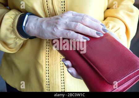 Frau, die eine dicke Brieftasche voller Bargeld in ihren Händen hält Stockfoto