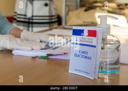 UNTERZEICHNUNG DER WÄHLERLISTE WÄHREND DER ERSTEN RUNDE DER KOMMUNALWAHLEN UNTER BEACHTUNG DER GESUNDHEITSMASSNAHMEN, DIE ANGESICHTS DER CORONAVIRUS-PANDEMIE, WAHLSTATION IN RUGLES, NORMANDIE, FRANKREICH, ERGRIFFEN WURDEN Stockfoto