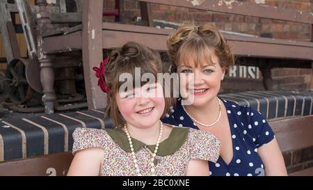 Lächelnde Mutter und Tochter zusammen, 1940er Frau & Mädchen in 1940er Mode, Severn Valley Railway Kriegszeit Sommer Veranstaltung, Kidderminster Station, Großbritannien. Stockfoto