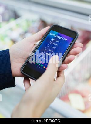 Nahaufnahme der Frau mit der digitalen Einkaufsliste auf dem Smartphone im Supermarkt Stockfoto