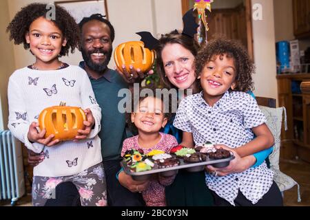 Porträt glückliche Familie mit geschnitzten Kürbissen und Halloween Cupcakes Stockfoto