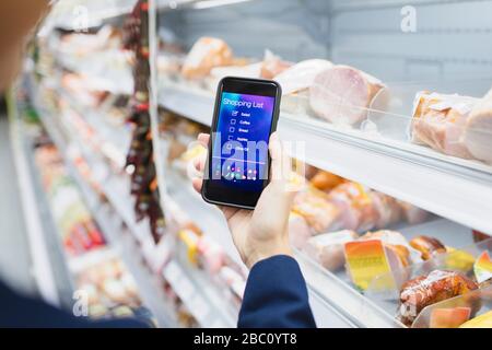 Frau verwendet digitale Einkaufsliste auf dem Kameratelefon im Supermarkt Stockfoto