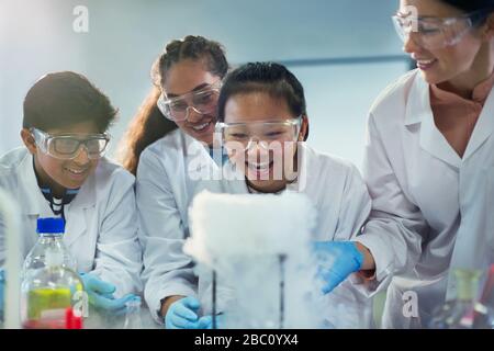 Neugierige, lächelnde Studenten beobachten chemische Reaktionen und führen wissenschaftliche Experimente im Laborunterricht durch Stockfoto