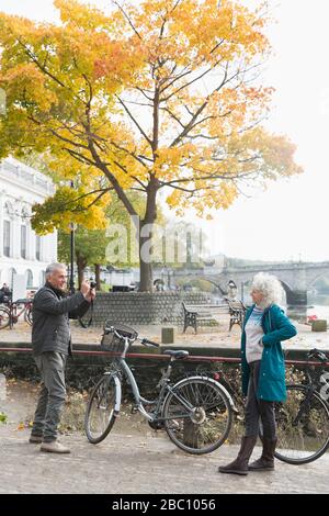 Leitender Mann fotografiert Frau mit dem Fahrrad in der Herbststadt Stockfoto