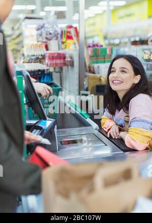 Freundliche Kassiererin hilft Kunden beim Supermarkt-Checkout Stockfoto