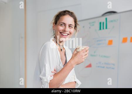 Selbstbewusste, lächelnde Geschäftsfrau, die im Konferenzraum Kaffee trinkt Stockfoto