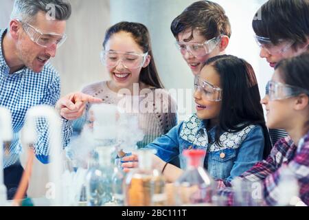 Lehrer und Schüler, die chemische Reaktionen beobachten und wissenschaftliche Experimente im Laborunterricht durchführen Stockfoto