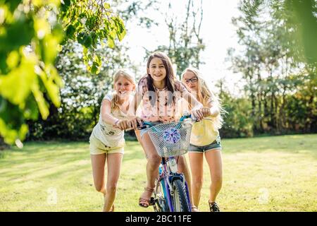 Glückliche Mädchen Fahrrad im Garten fahren Stockfoto