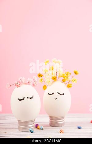 Ein süßes weißes Osterei mit geschlossenen Augen in Kränzen kleiner bunter Blumen. Stockfoto