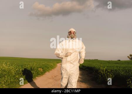 Mann mit Schutzanzug und Maske läuft auf dem Land Stockfoto