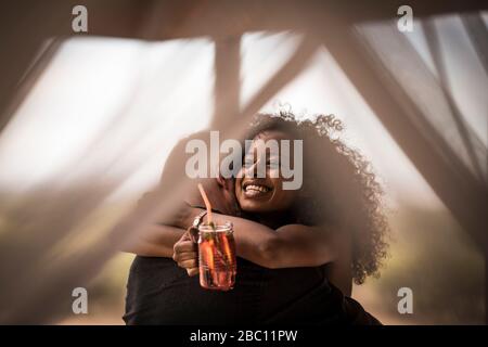 Glückliche Frau hält frischen Eistee trinken umarmenden Mann Stockfoto