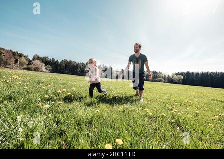 Vater und kleine Tochter haben Spaß zusammen auf einer Wiese im Frühjahr Stockfoto
