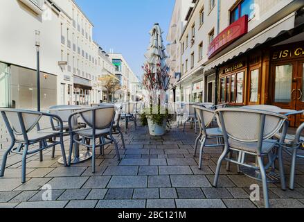 Café im Freien. Leere Tische im Restaurant. Coronavirus-Effekt. Eine verlassene Stadt in Deutschland. Frühling in der Stadt. Sonne und Himmel. Stockfoto