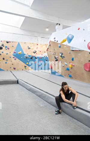 Frau, die sich auf das Klettern an der Wand vorbereitet und Schuhe anzieht Stockfoto