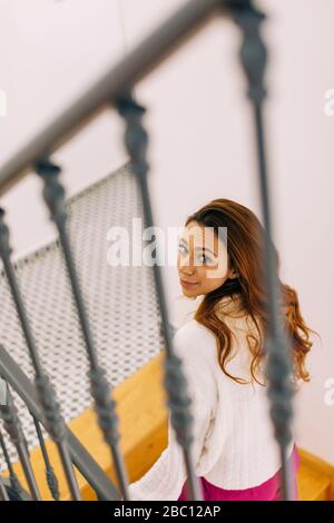 Porträt einer jungen Frau im Treppenhaus, die nach oben schaut Stockfoto