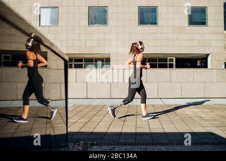 Sportliche junge Frau mit Beinprothese in der Stadt laufen Stockfoto