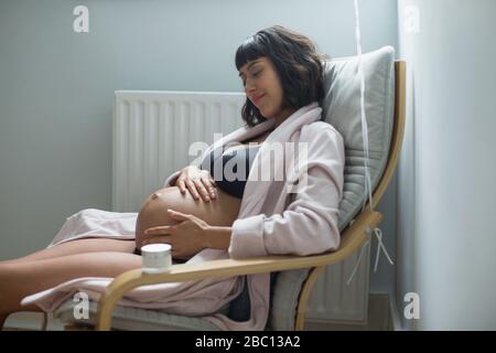 Ruhige schwangere Frau reibt Magen Stockfoto