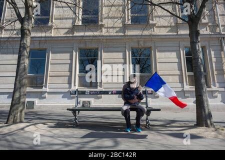 Paris, Frankreich. März 2020. April 2020 sitzt ein Junge mit französischer Flagge auf dem Schoß seines Vaters auf einer Bank nahe dem Krankenhaus Pitié Salpêtriére in Paris, Frankreich. (Foto von Daniel Brown/Sipa USA) Credit: SIPA USA/Alamy Live News Stockfoto