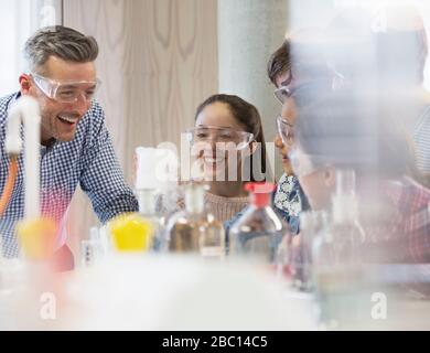 Männliche Wissenschaftslehrerin und Studenten lachen und führen wissenschaftliche Experimente im Laborunterricht durch Stockfoto