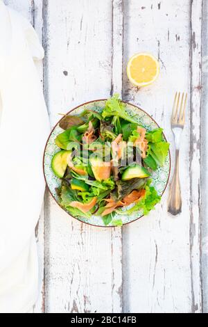 Teller mit verzehrfertigen grünen Salaten mit Rucola, Lollo Rosso Salat, Babyspinat, Rote Bete Blätter, Avocado, Maissalat und Lachs Stockfoto