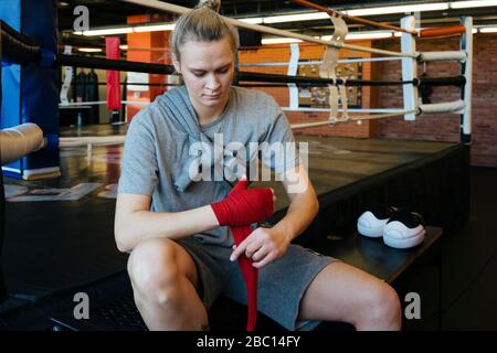 Junge Frau, die im Boxclub einen Verband um die Hand bindet Stockfoto