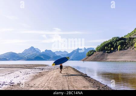 Mann, der SUP-Board zum See trägt Stockfoto