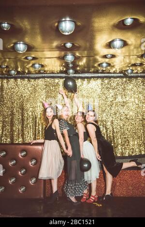 Porträt von vier glücklichen Frauen, die in einem Club Partyhüte tragen Stockfoto