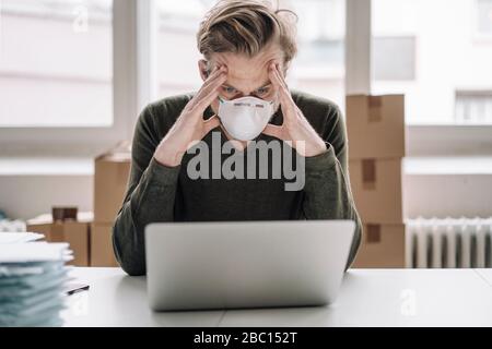 Ernst Geschäftsmann tragen Schutzmaske und mit Laptop Stockfoto