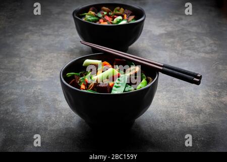 Zwei Schalen verzehrfertige Miso-Suppe mit udon-Nudeln, Tofu, Zuckererbsen, Paprika, Karotten, Mu-Err-Pilzen, Kopfzbarren und Koriander Stockfoto